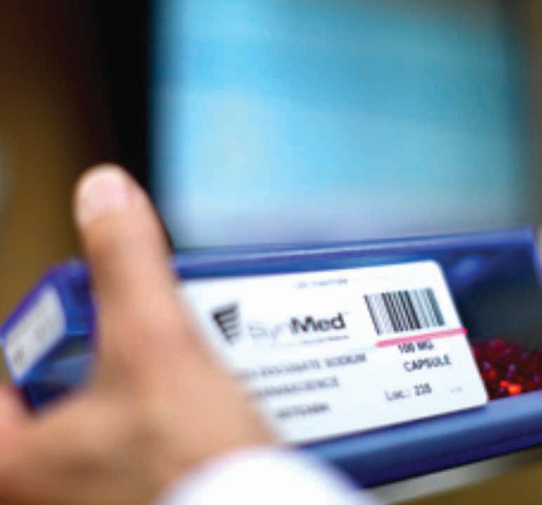 A pharmacist holding a barcoded multi-dose blister card during verification.